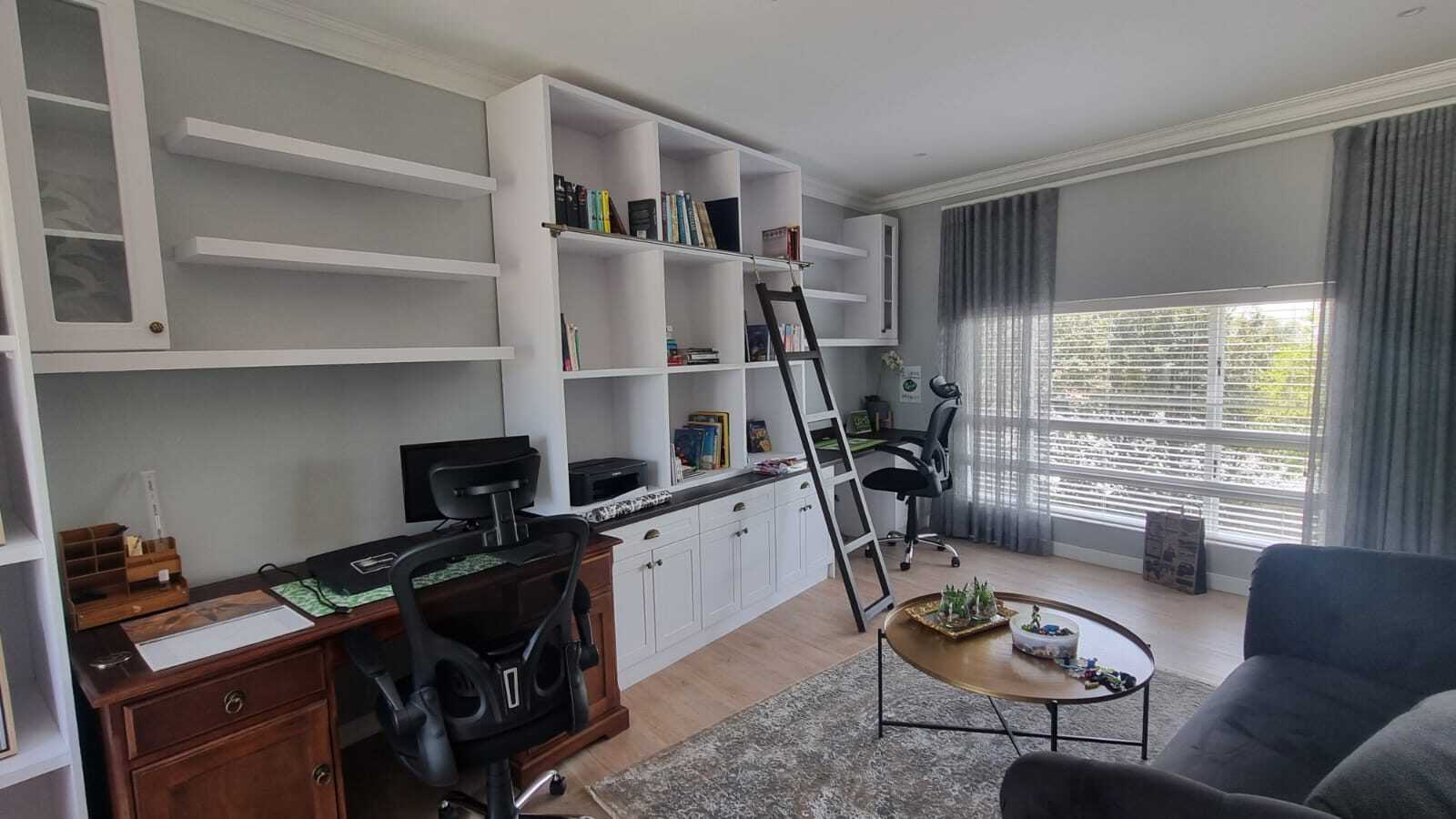 Built-in study wall with shelving, desk and ladder, wide view